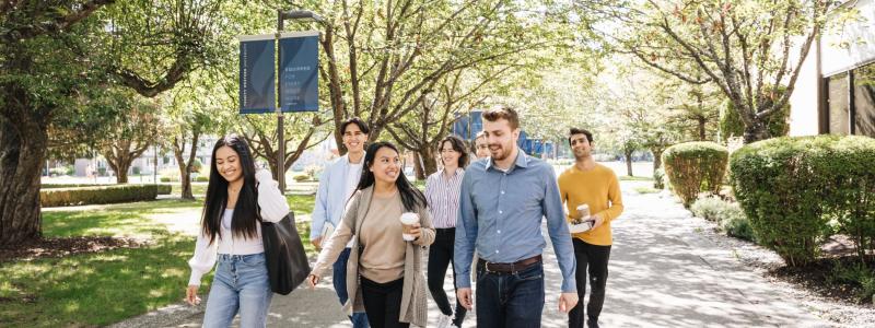 Students walking down main pathway at TWU smiling and talking.