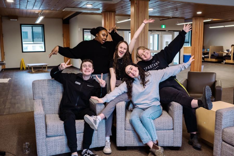students smiling in a group photo with their hands raised