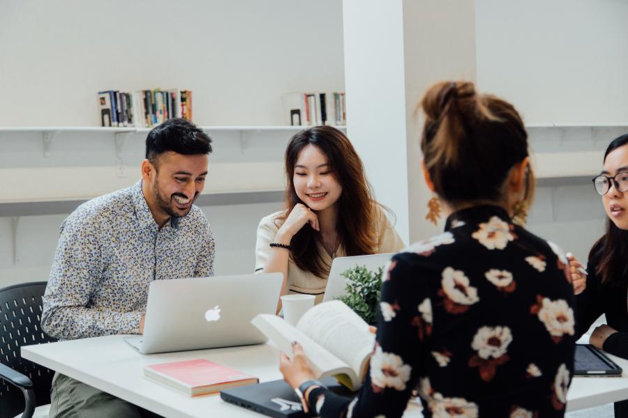 students smiling at laptop and working at a table