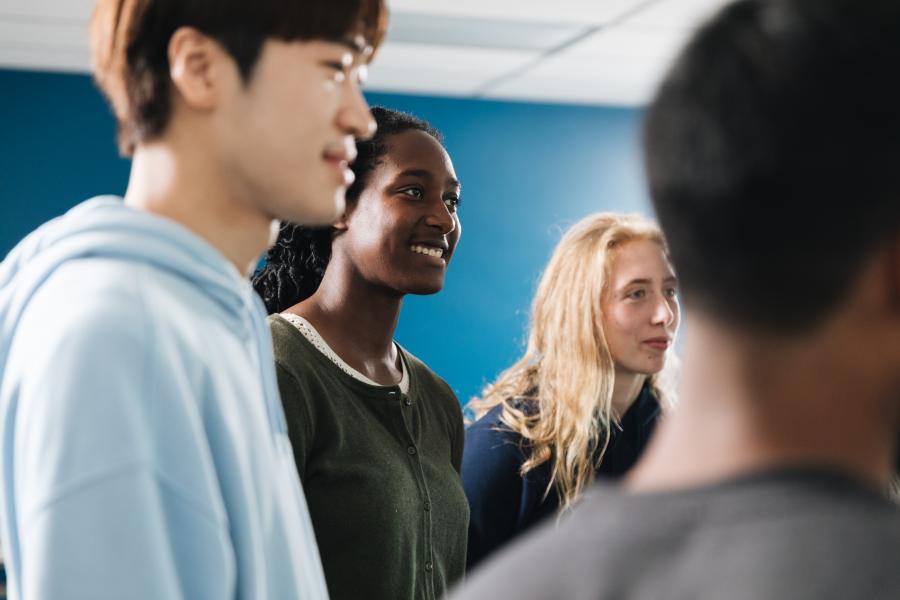 A group of young people standing together in a room with blue walls and a white ceiling.